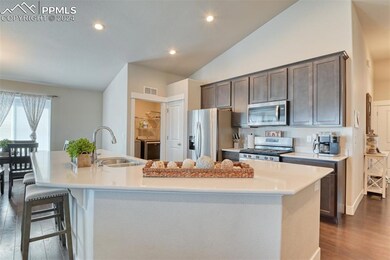 Kitchen with stainless steel appliances, sink, dark hardwood / wood-style floors, lofted ceiling, and an island with sink