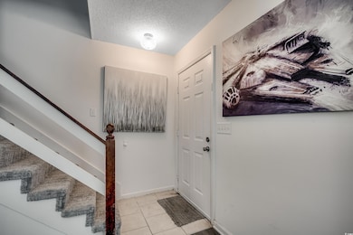 Foyer featuring stairs, tile patterned flooring, a textured ceiling, and baseboards