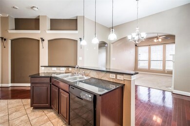 Kitchen with sink, hanging light fixtures, black dishwasher, ceiling fan, and light hardwood / wood-style floors