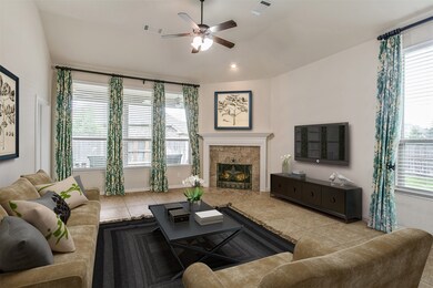 The light and bright spacious living room is a perfect layout for entertaining or simply relaxing! Whether it is a simple night in or entertaining family and friends, this home has space for everyone to enjoy, featuring gorgeous fireplace, dark stained ceiling fan, tile flooring, large windows with blinds, high ceilings, and recessed lighting!