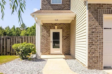 Entrance to property featuring brick siding, fence