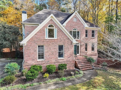 View of front of house featuring brick siding, a chimney, and roof with shingles