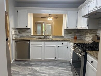 Kitchen with stainless steel appliances, a sink, white cabinetry, and decorative backsplash