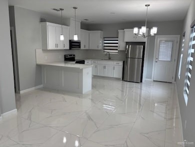 Kitchen featuring stainless steel appliances, baseboards, a sink, a peninsula, and light countertops