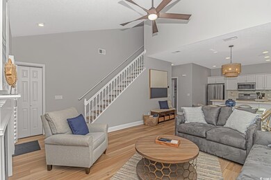 Living room with light hardwood / wood-style flooring, ceiling fan, and high vaulted ceiling