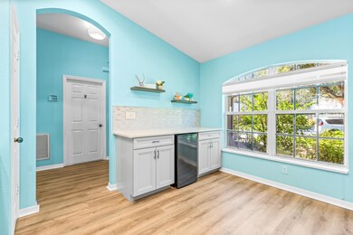 Kitchen with tasteful backsplash, open shelves, light wood finished floors, white cabinetry, and wine cooler