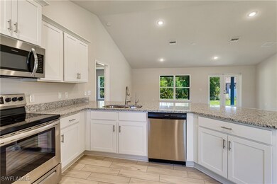 Kitchen with white cabinets, appliances with stain
