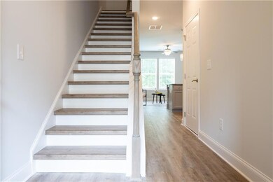 Staircase with wood finished floors and a ceiling fan
