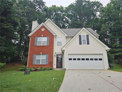 Traditional-style home featuring concrete driveway, brick siding, a chimney, and a front yard
