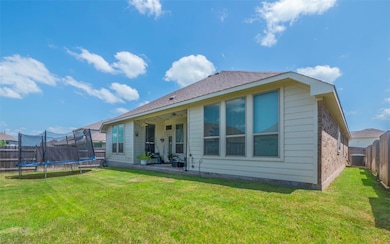 Back of property featuring a patio area, a trampoline, a fenced backyard, and roof with shingles