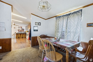 Dining space with wooden walls, a wainscoted wall, crown molding, a chandelier, and carpet flooring