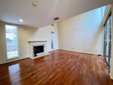 Formal living with wood burning fireplace, wood floors, and high ceilings.