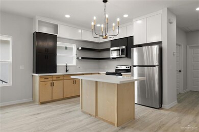 Kitchen featuring stainless steel appliances, open shelves, light wood-style flooring, light brown cabinets, and light countertops