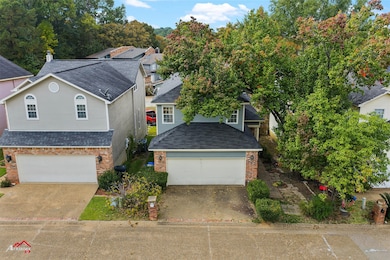 Traditional home featuring a shingled roof, a garage, driveway, and brick siding