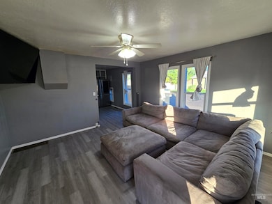 Living room featuring a textured ceiling, wood finished floors, and ceiling fan