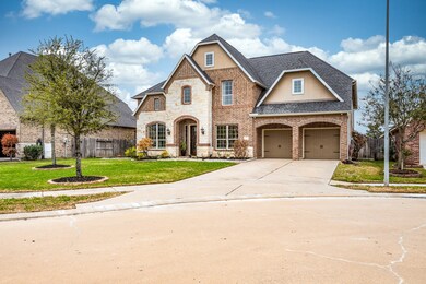 Beautiful brick and stone two-story elevation showcases a large driveway, double porte-cochere and 3-car tandem garage featuring epoxy floors and built-ins.