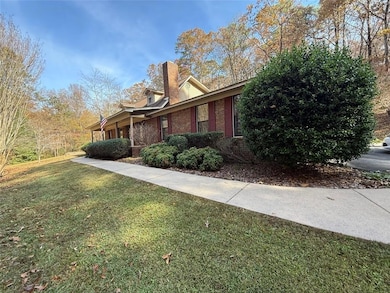 View of side of property featuring a yard, a chimney, a porch, and brick siding