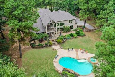 Aerial view of the back of the house showing the swimming pool and covered porch and balcony areas.