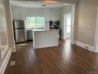 Kitchen with dark hardwood / wood-style floors, tasteful backsplash, light stone countertops, a center island, and appliances with stainless steel finishes