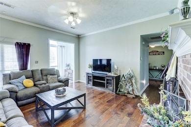 Living area featuring visible vents, crown molding
