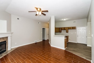 Unfurnished living room with ceiling fan, a fireplace, and dark wood-type flooring