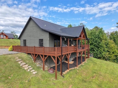 Rear view of house with a deck, a lawn, a metal roof, and log veneer siding