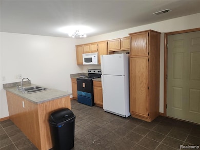 Kitchen featuring white appliances, light countertops, a peninsula, and dark tile patterned flooring