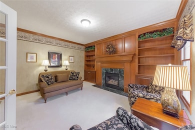 Designated Office/ Den or Living room with french doors, crown molding, built-in shelves, and gas fireplace.