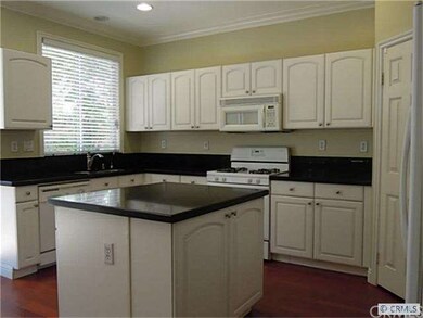 The kitchen has white Euro cabinetry, rich black q