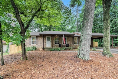 Ranch-style home featuring brick siding, an attached carport, and covered porch