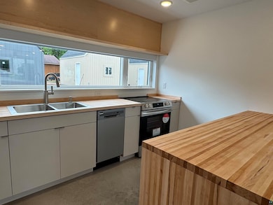 Kitchen with finished concrete floors, stainless steel appliances, and butcher block counters