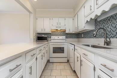 Kitchen featuring white cabinetry, tasteful backsp