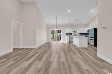 Unfurnished living room featuring high vaulted ceiling, a chandelier, recessed lighting, and light wood-style floors