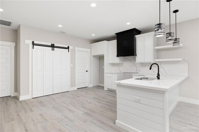 Kitchen featuring sink, a barn door, tasteful backsplash, and light wood-style tile flooring