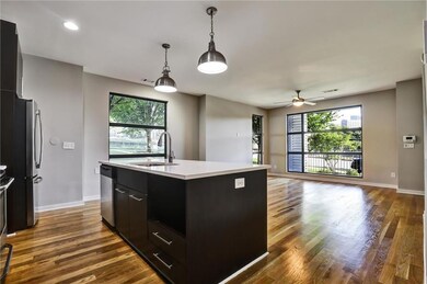 Kitchen with dark cabinetry, light countertops, dark wood finished floors, appliances with stainless steel finishes, and plenty of natural light