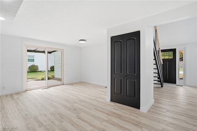 Unfurnished room featuring stairway and light wood-type flooring