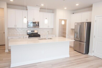 Kitchen featuring appliances with stainless steel finishes, a sink, a kitchen island with sink, tasteful backsplash, and recessed lighting