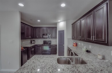 Kitchen with black appliances, sink, light stone c