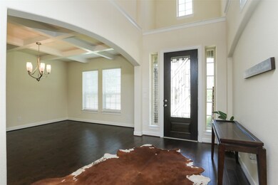 The impressive foyer welcomes your guests with lovely wood flooring. The formal dining room is open to the entry with dramatic cross beam ceiling.