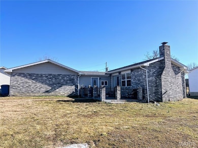 Rear view of house featuring brick siding, a lawn, and a chimney