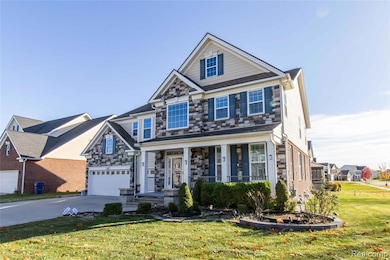 Craftsman-style house with covered porch, a front yard, stone siding, a garage, and driveway