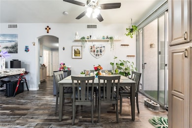 Dining room with arched walkways, dark wood-type flooring, and a ceiling fan