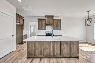 Kitchen with light wood-style flooring, light countertops, a kitchen island with sink, backsplash, and recessed lighting