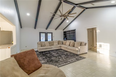 Living area with beamed ceiling, high vaulted ceiling, a ceiling fan, recessed lighting, and french doors