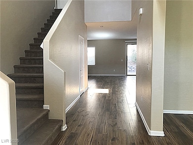 Hall with a textured wall, dark wood-style flooring, and stairs