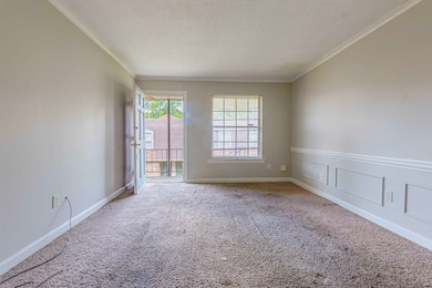 Spare room featuring a textured ceiling, crown molding, and carpet floors