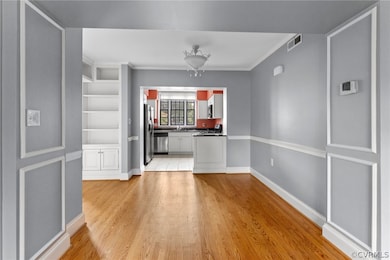 Kitchen with white cabinetry, crown molding, light