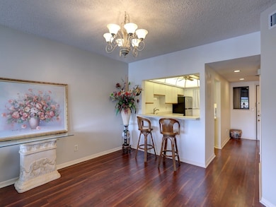 Kitchen with a breakfast bar area, light countertops, dark wood-type flooring, a peninsula, and freestanding refrigerator