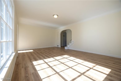Unfurnished room featuring arched walkways and wood finished floors
