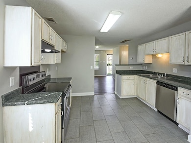 Kitchen with visible vents, a sink, a peninsula, u